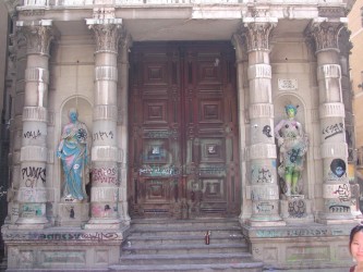 Old building with pillars and statues covered in graffiti